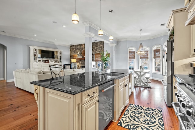 kitchen with decorative light fixtures, cream cabinets, hardwood / wood-style flooring, and a center island with sink