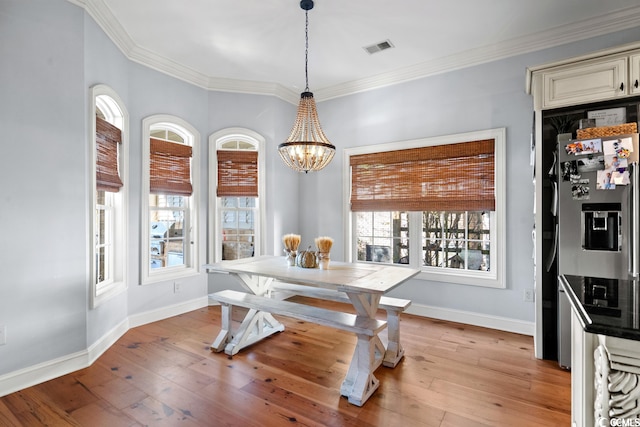 dining room featuring light wood-type flooring, a wealth of natural light, a chandelier, and crown molding