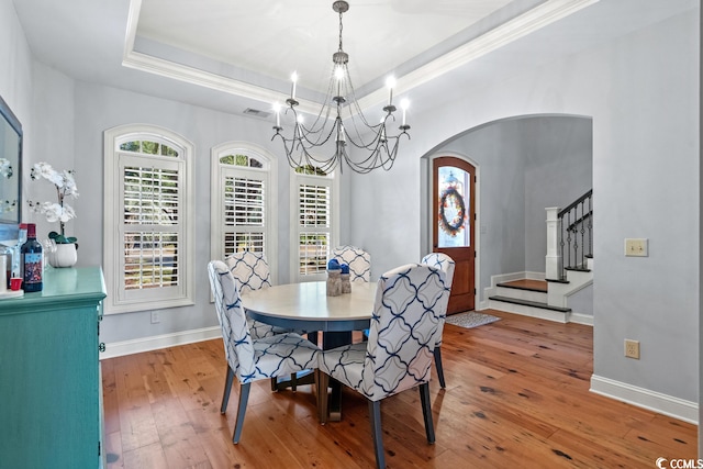 dining room featuring a tray ceiling, ornamental molding, wood-type flooring, and a notable chandelier