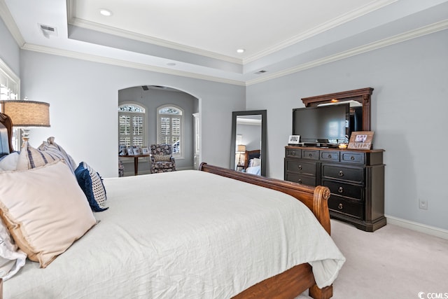 bedroom with ornamental molding, light carpet, and a tray ceiling