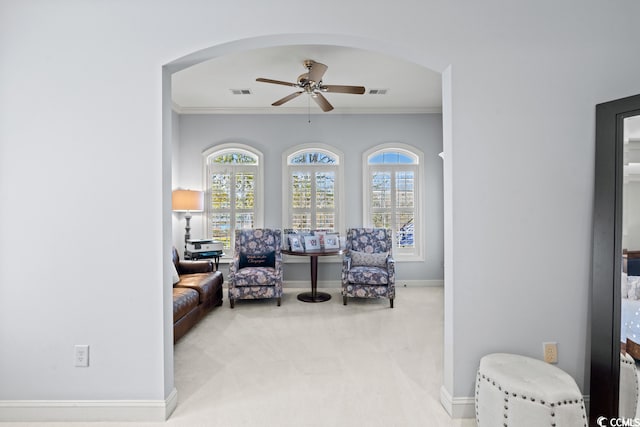 living area featuring crown molding, carpet flooring, and ceiling fan