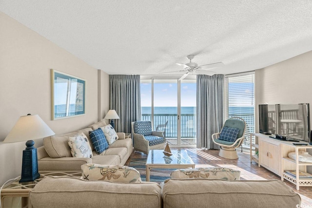 living room with ceiling fan, a healthy amount of sunlight, and a textured ceiling