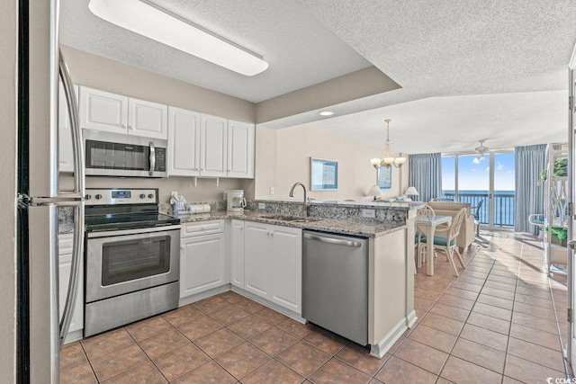 kitchen featuring white cabinets, sink, a textured ceiling, appliances with stainless steel finishes, and kitchen peninsula