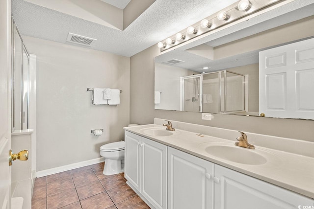 bathroom with tile patterned floors, an enclosed shower, vanity, a textured ceiling, and toilet