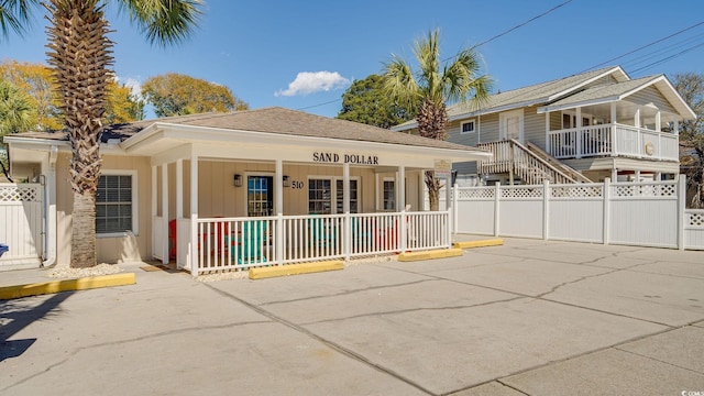 view of front of home with covered porch, fence, and roof with shingles