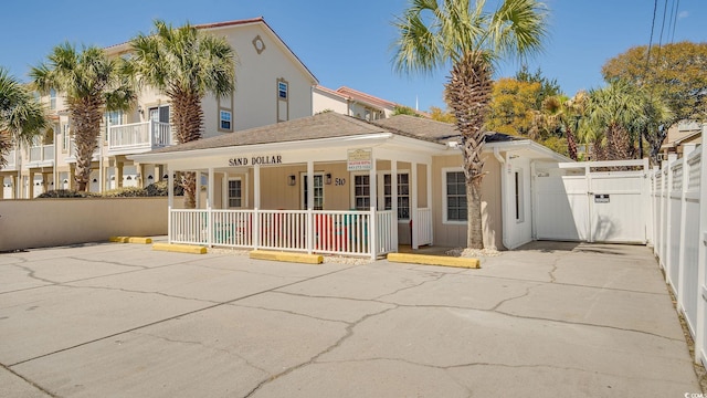 view of front of home featuring covered porch, a gate, fence, and uncovered parking