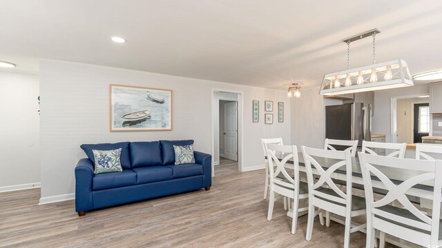 dining room featuring light wood finished floors, baseboards, and recessed lighting