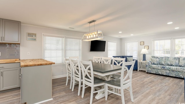 dining area with a wealth of natural light, crown molding, light wood-style flooring, and recessed lighting