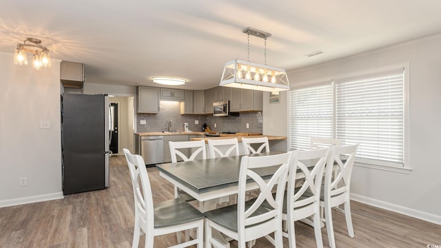 dining space with light wood-type flooring, visible vents, and baseboards