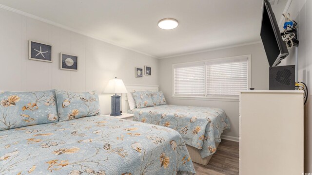 bedroom featuring baseboards, ornamental molding, and wood finished floors