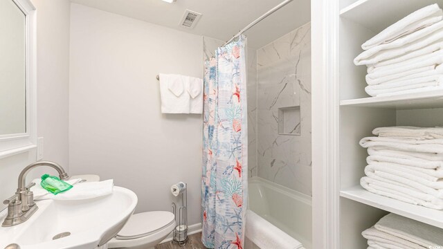 full bathroom featuring toilet, sink, hardwood / wood-style floors, and shower / tub combo with curtain