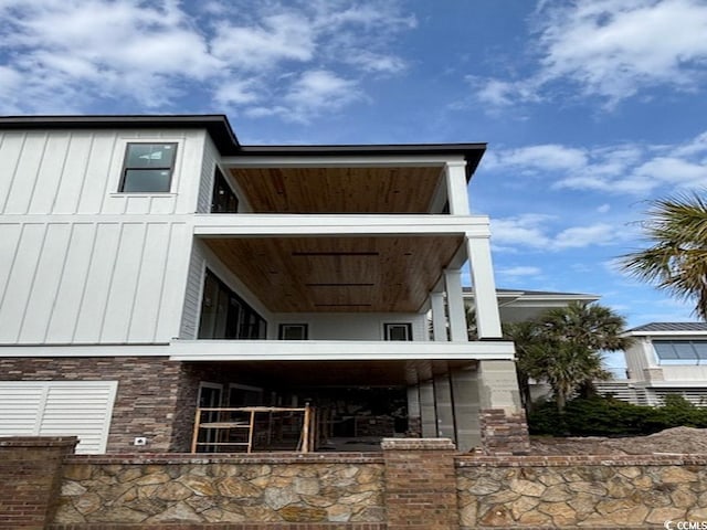 4300 N Ocean Blvd, Myrtle Beach, SC 29577 - rear view of house featuring a balcony, stone siding, and board and batten siding