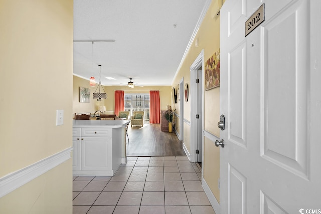 kitchen featuring ceiling fan, white cabinetry, ornamental molding, and light tile floors