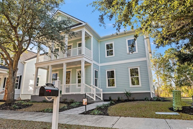 view of front of property with covered porch, a balcony, and a front lawn