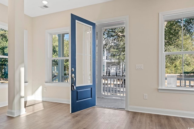 doorway featuring light wood-style flooring, visible vents, and baseboards