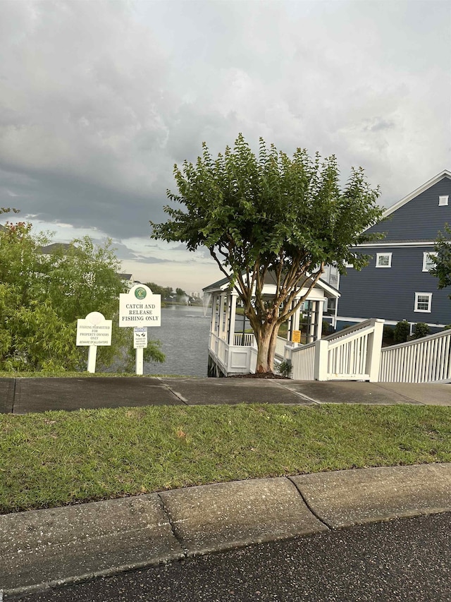 view of front of property with a front lawn, a water view, and fence