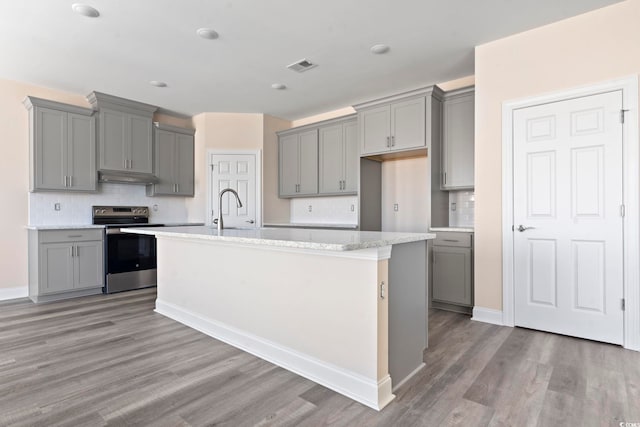 kitchen featuring an island with sink, stainless steel electric range oven, sink, and gray cabinetry