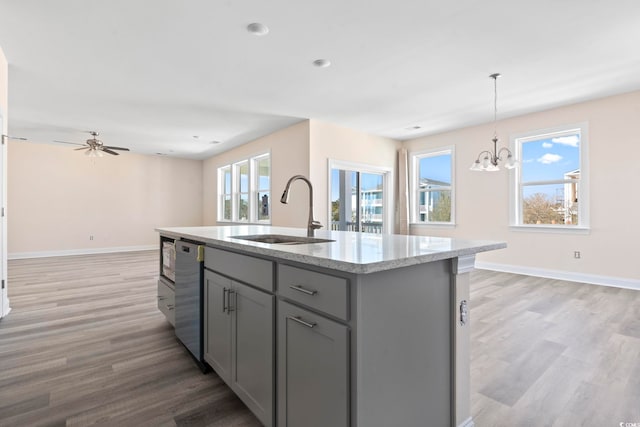 kitchen with a center island with sink, gray cabinetry, pendant lighting, sink, and a healthy amount of sunlight