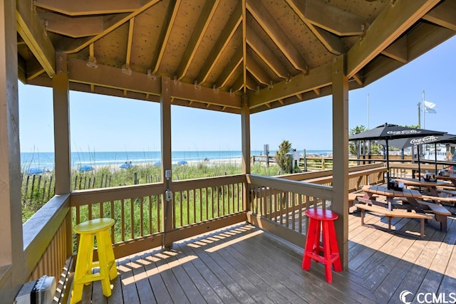 wooden terrace with a water view, a beach view, and a gazebo