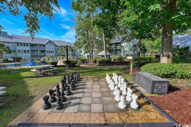 view of property's community with a swimming pool, a residential view, fence, and a lawn