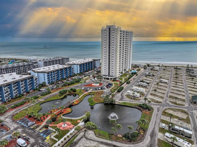 aerial view at dusk featuring a view of the beach and a water view