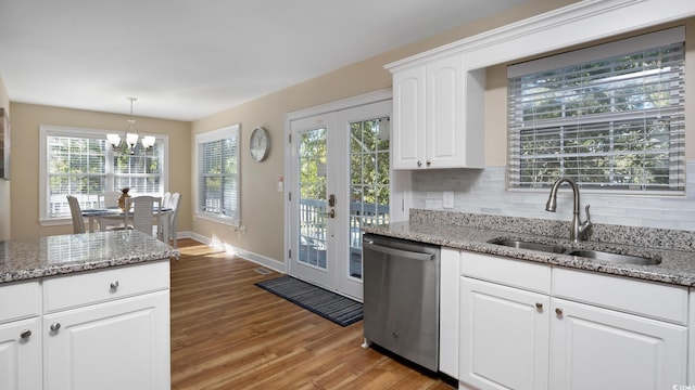 kitchen with tasteful backsplash, light wood-style flooring, white cabinets, a sink, and dishwasher