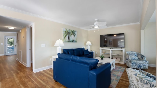 living room with ornamental molding, a ceiling fan, baseboards, and wood finished floors