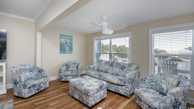 living area featuring crown molding, baseboards, ceiling fan, and wood finished floors