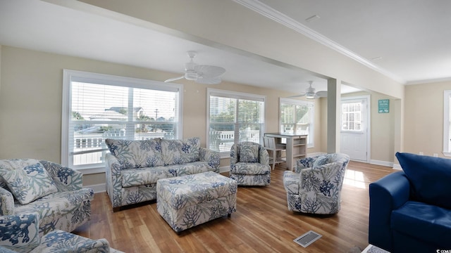 living area with visible vents, crown molding, baseboards, and wood finished floors