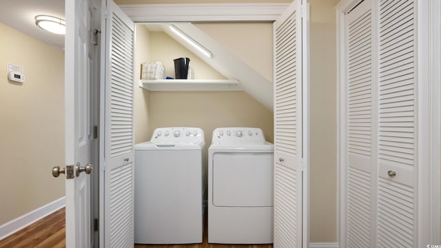 washroom featuring washer and dryer, laundry area, baseboards, and wood finished floors