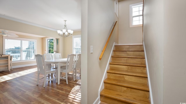 staircase featuring an inviting chandelier, baseboards, ornamental molding, and wood finished floors