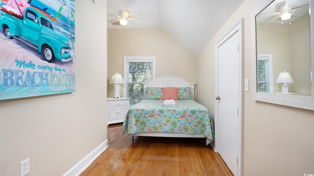 bedroom with a ceiling fan, lofted ceiling, baseboards, and hardwood / wood-style flooring