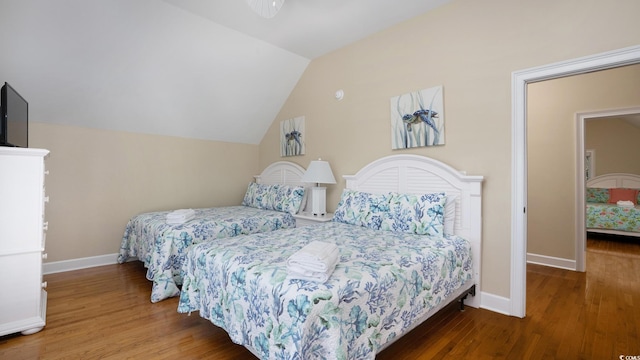 bedroom featuring vaulted ceiling, baseboards, and wood finished floors