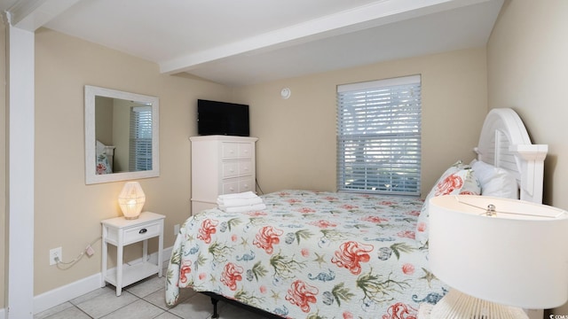 bedroom with beamed ceiling, baseboards, and tile patterned floors