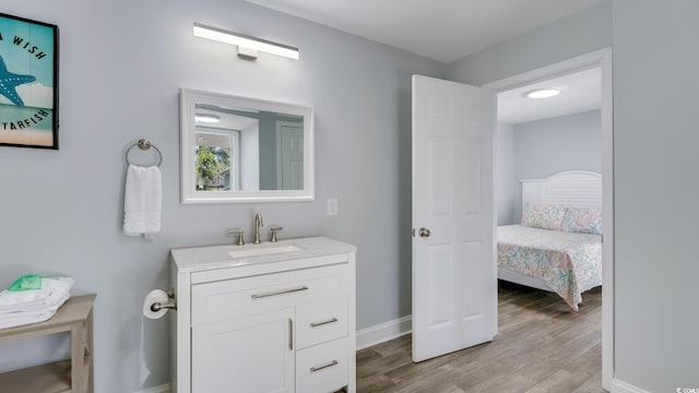 bathroom with wood finished floors, vanity, and baseboards