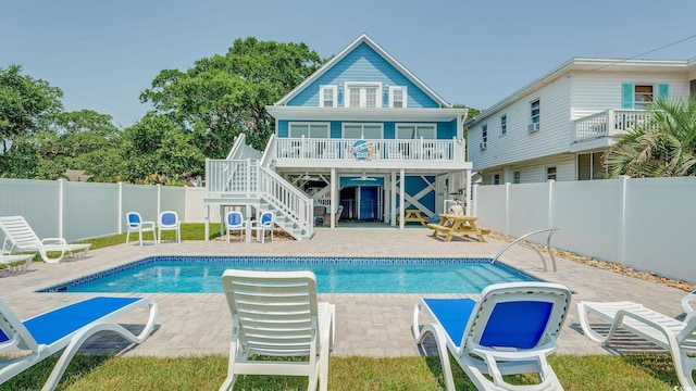 rear view of house featuring a fenced in pool, a fenced backyard, a patio, and stairs