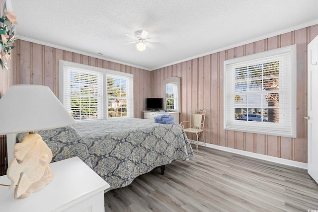 bedroom featuring wood walls, ceiling fan, and light wood-type flooring