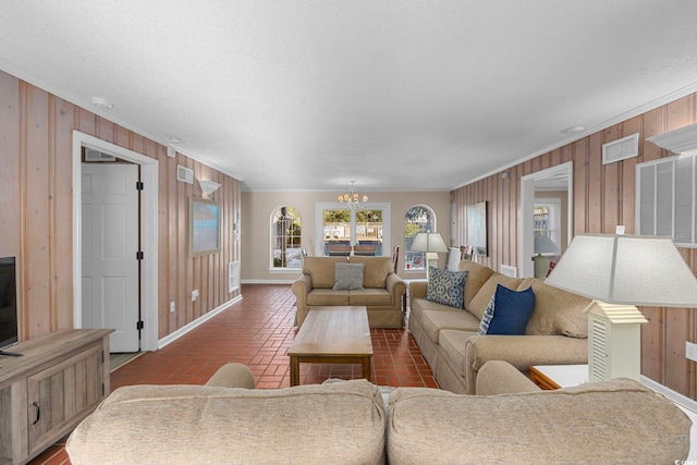 living room featuring crown molding, an inviting chandelier, a textured ceiling, and wood walls