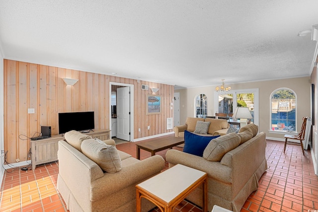 living room with a notable chandelier, wood walls, ornamental molding, and a textured ceiling