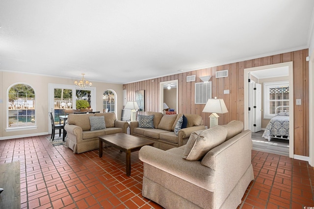 living room featuring an inviting chandelier, crown molding, and wood walls