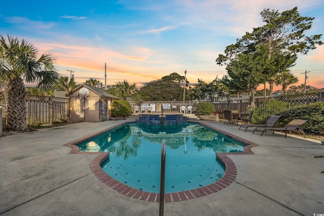 pool at dusk featuring an outdoor structure and a patio area