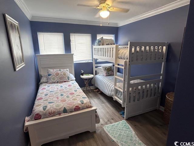 bedroom with dark hardwood / wood-style floors, ceiling fan, and ornamental molding