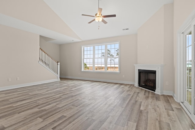 unfurnished living room with a fireplace, light wood finished floors, visible vents, stairway, and vaulted ceiling