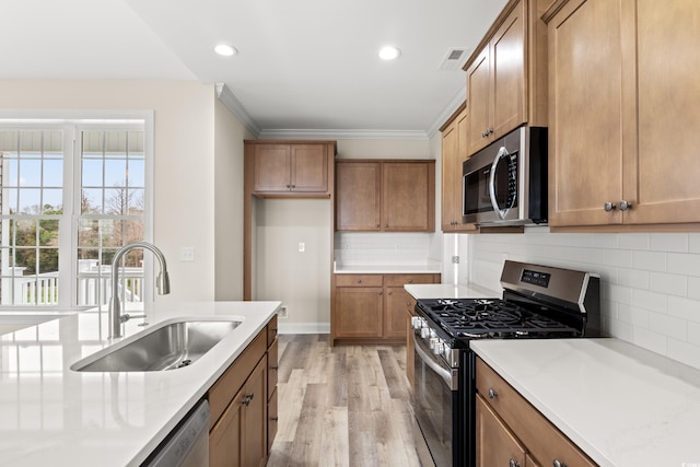 kitchen featuring visible vents, appliances with stainless steel finishes, brown cabinetry, and a sink