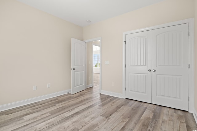 unfurnished bedroom with light wood-style floors, a closet, and baseboards