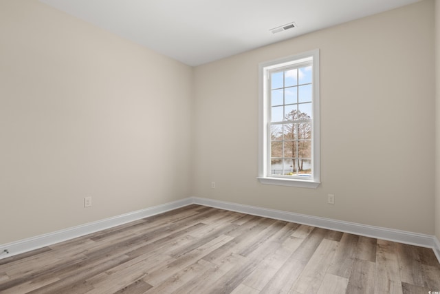 spare room featuring light wood-style floors, baseboards, and visible vents