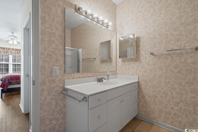 bathroom with ensuite bathroom, vanity, baseboards, a ceiling fan, and wallpapered walls