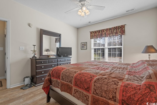 bedroom featuring a textured ceiling, ceiling fan, light wood-style flooring, visible vents, and baseboards