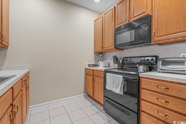 kitchen featuring baseboards, light countertops, black appliances, and light tile patterned flooring