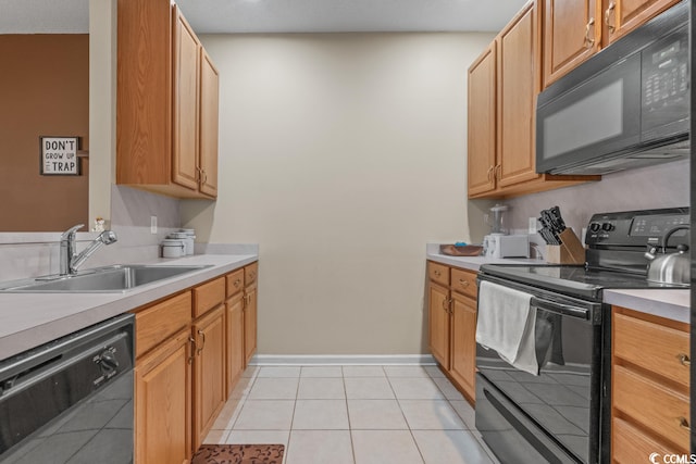 kitchen featuring light tile patterned floors, baseboards, light countertops, black appliances, and a sink